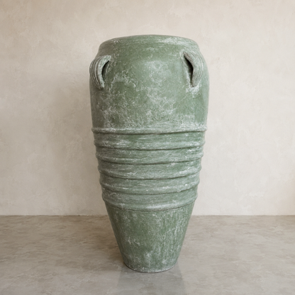 The Athens Organic Fiberglass Pot - Earth Range by Florastyle By Hingham features a large green weathered finish, dual small top handles, and horizontal mid-ridges. It sits on a smooth light-toned surface against a neutral wall.
