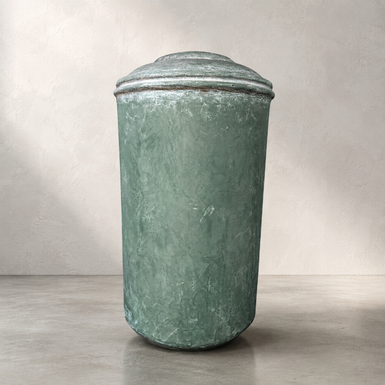The Damascus Organic Fiberglass Pot - Earth Range by Florastyle By Hingham, a large cylindrical green planter with a domed lid, sits on concrete against a beige wall, resembling modern interior decor.