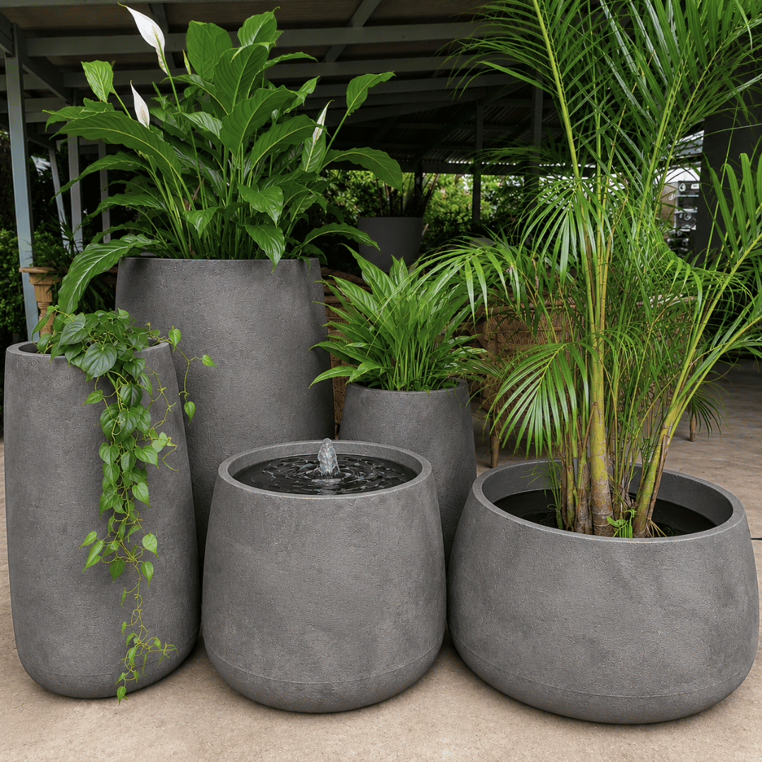 The Florastyle By Hingham Full Bios Set features five large, modern UV-resistant polyresin planters with lush tropical plants and one Bios Medium water feature, arranged stylishly on a covered patio area.