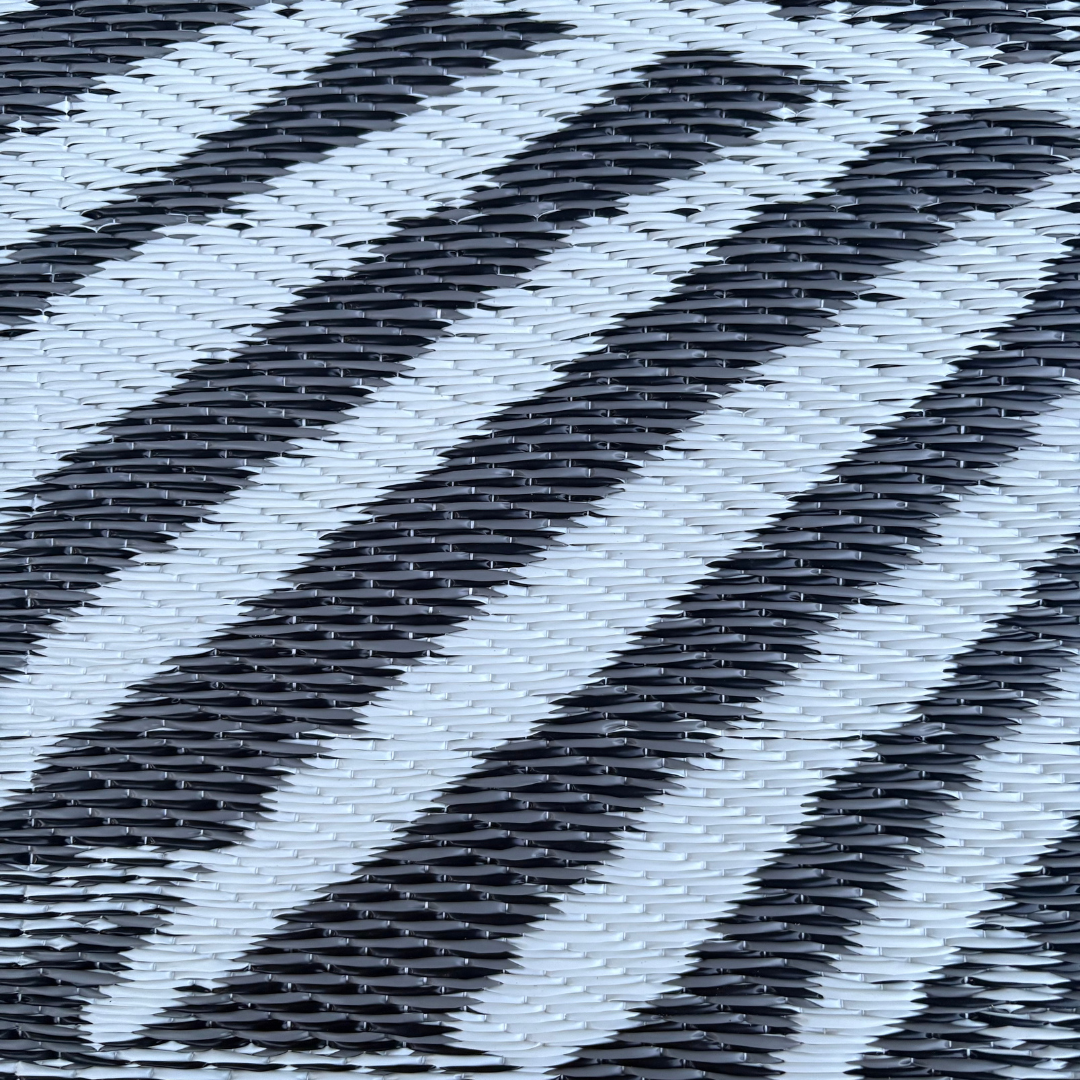 Close-up of the Florastyle By Hingham Medium Hanoi Outdoor Reversible Mat shows its lightweight, double woven black and white surface with diagonal zigzag stripes for a textured, dynamic look. Water-resistant design enhances durability and style.