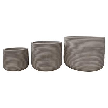 Three gray, ribbed, cylindrical Lagoon Round Japi Planters by Florastyle By Hingham in assorted sizes are arranged from smallest to largest against a white background, providing a modern planter aesthetic that complements any space.