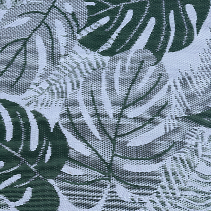 Close-up of Florastyle By Hingham’s Medium Lima Outdoor Reversible Mat, featuring lightweight, double-woven fabric with a large green monstera and fern motif on a light background. Water-resistant design delivers a textured, tropical look.