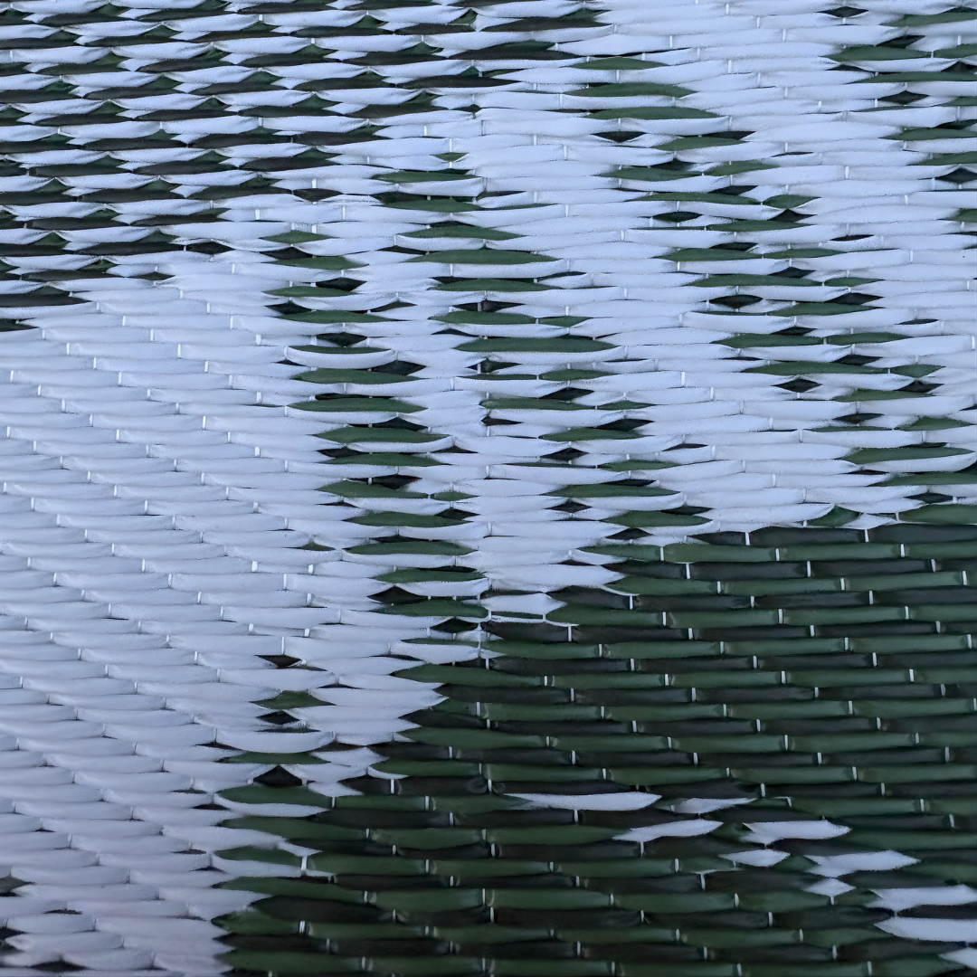 Close-up of the Florastyle By Hingham Medium Lima Outdoor Reversible Mat, featuring a lightweight, double woven design with a diagonal white and green zigzag pattern for a modern, geometric look. Water resistant and perfect for outdoor use.