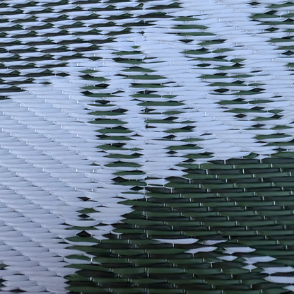 Close-up of the Florastyle By Hingham Medium Lima Outdoor Reversible Mat, featuring a lightweight, double woven design with a diagonal white and green zigzag pattern for a modern, geometric look. Water resistant and perfect for outdoor use.