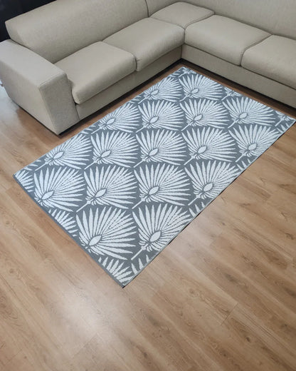 A Medium Mumbai Outdoor Reversible Mat by Florastyle By Hingham, featuring a lightweight double-woven design and water resistance, is placed on a light wood floor next to a beige L-shaped sofa.