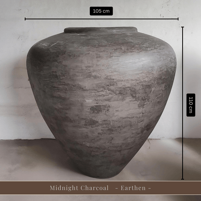 A large, gray Mykonos Organic Fiberglass Pot - Earth Range by Florastyle By Hingham (105 cm W x 110 cm H) stands out with its lightweight build and subtle elegance. Midnight Charcoal - Earthen - is displayed at the bottom.