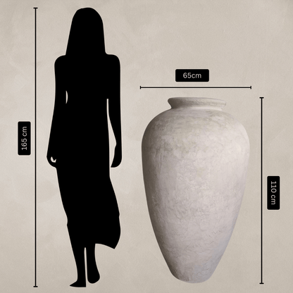 A 165cm-tall woman stands next to the Florastyle By Hingham Rhodes Organic Fiberglass Pot - Earth Range, which is white, lightweight, 110cm tall and 65cm wide; both shown against a plain background with measurement labels.