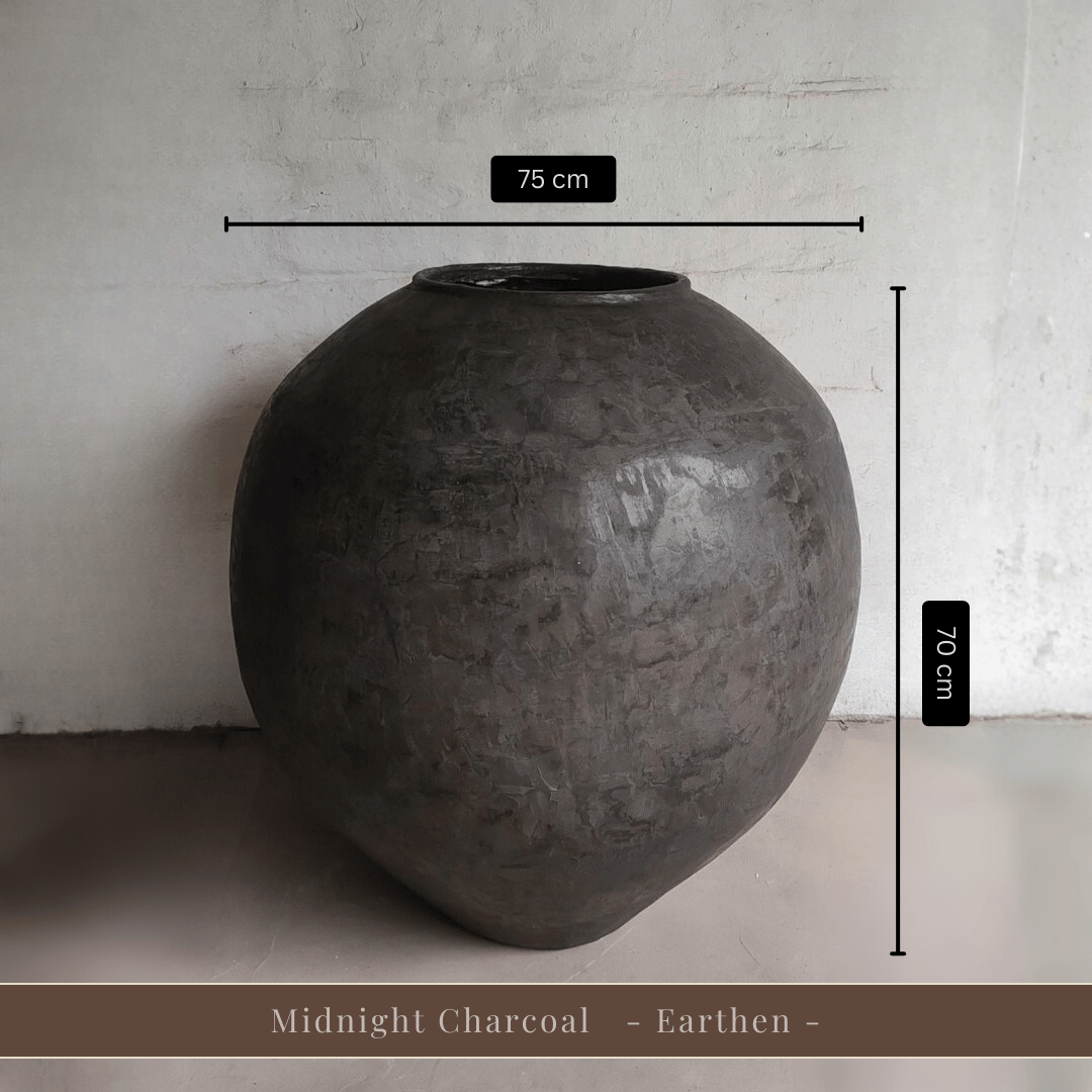 A large, dark, round fiberglass pot labeled Syracuse Organic from Florastyle By Hingham stands against a light wall. Despite its size—75 cm wide and 70 cm tall—it is surprisingly lightweight. Text at the bottom reads Syracuse Organic - Earth Range -.