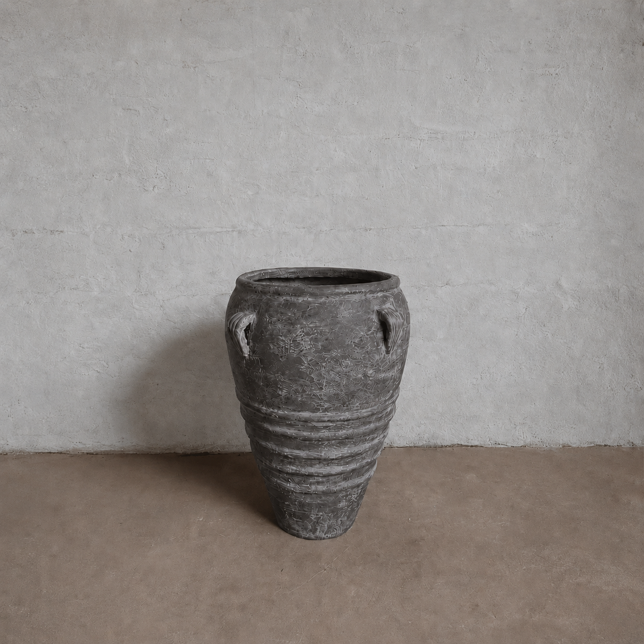 The Athens Organic Fiberglass Pot – Earth Range by Florastyle By Hingham, featuring two small handles and horizontal ridges, sits on a brown floor against a textured light gray wall, echoing ancient Greek pottery.