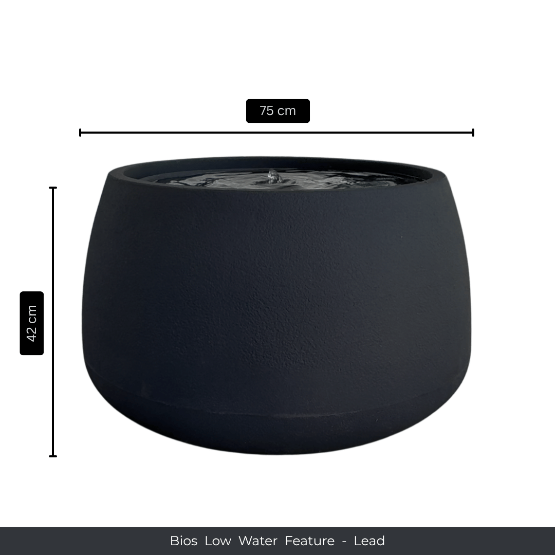 A round, dark gray water feature with a smooth finish, filled with water—ideal as an indoor fountain. Dimensions: 75 cm W x 42 cm H. Text below reads: Water Feature - Bios Low by Florastyle By Hingham. Made from polyresin, durable and waterproof, yet lightweight. Suitable for indoor and outdoor spaces.
Colour: Lead
Price: R5195