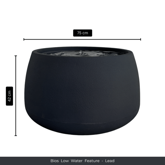 A round, dark gray water feature with a smooth finish, filled with water—ideal as an indoor fountain. Dimensions: 75 cm W x 42 cm H. Text below reads: Water Feature - Bios Low by Florastyle By Hingham. Made from polyresin, durable and waterproof, yet lightweight. Suitable for indoor and outdoor spaces.
Colour: Lead
Price: R5195