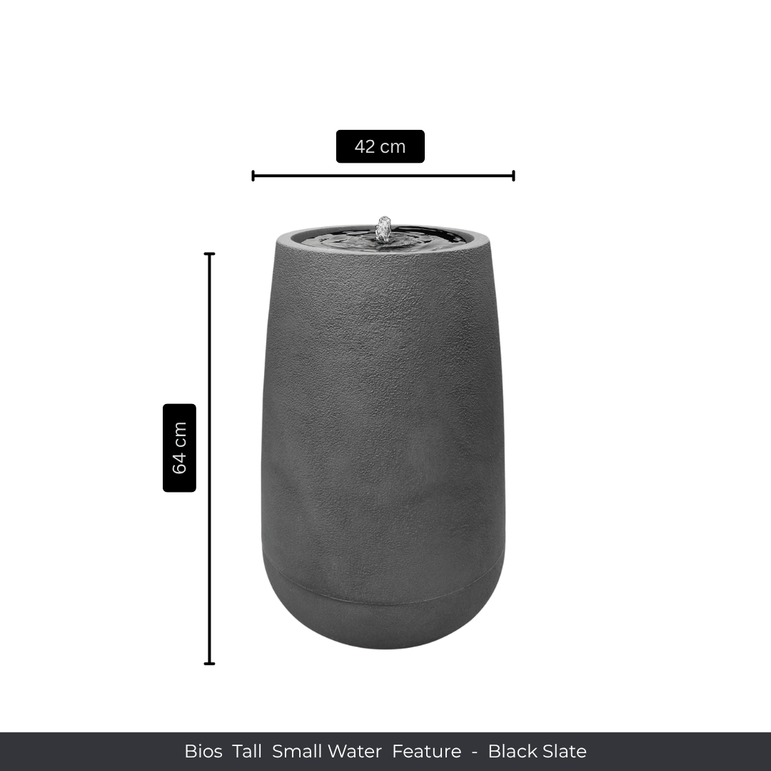 The Water Feature - Bios Tall Small by Florastyle By Hingham is a tall, cylindrical black slate fountain with water bubbling at the top, suitable for indoors or outdoors. Measures 64 cm high and 42 cm wide. Shown on a plain white background with labeled dimensions. Made from polyresin, durable and waterproof, yet lightweight. Suitable for indoor and outdoor spaces.
Colour: Black Slate
Price: R4045