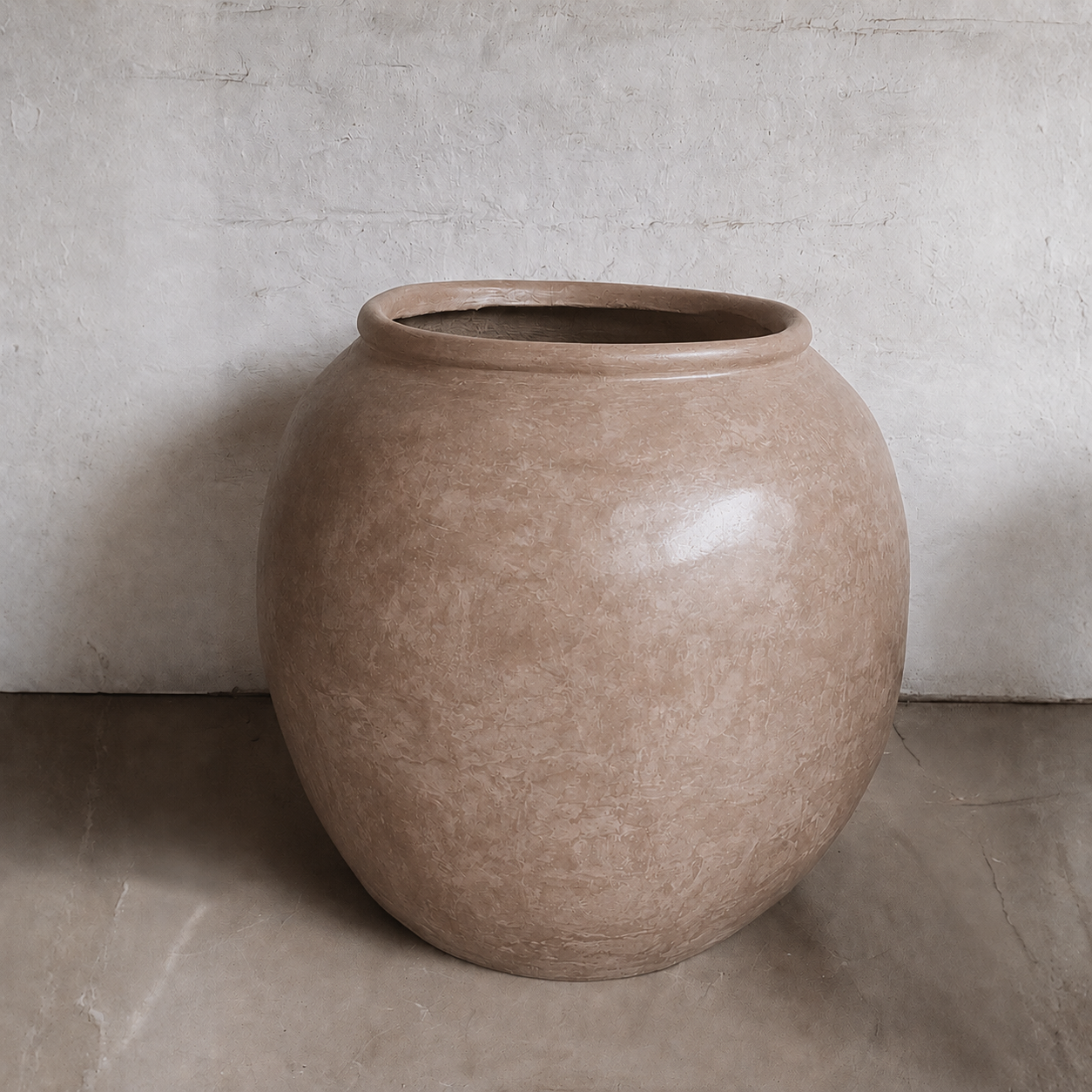 The Florastyle By Hingham Delphi Organic Fiberglass Pot - Earth Range is a large, round planter with a smooth, slightly glossy light brown finish, wide opening, and sits on a neutral floor against a pale textured wall.