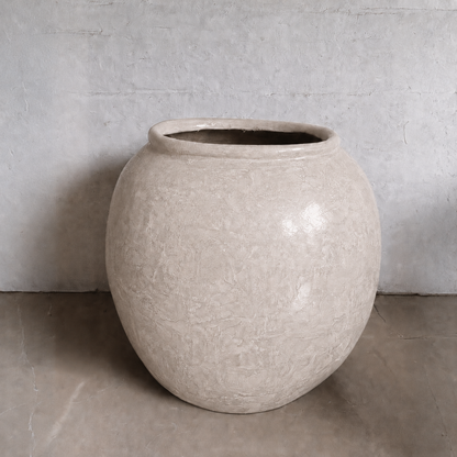 The Delphi Organic Fiberglass Pot - Earth Range by Florastyle By Hingham features a textured beige finish and round shape, creating an elegant accent on any floor or against light gray walls—perfect for stylish, modern spaces.