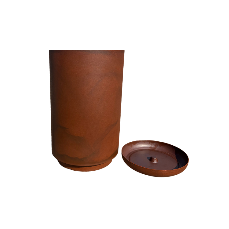 A tall, cylindrical brown Match Cylinder Japi Planter With Saucer by Florastyle By Hingham stands on a white background, with its matching round lid featuring a small raised center placed beside it.