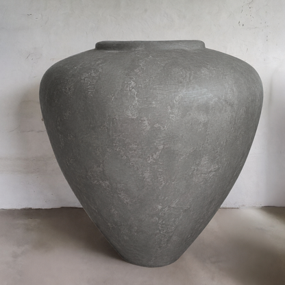The Mykonos Organic Fiberglass Pot - Earth Range by Florastyle By Hingham features a large, smooth grey design with a wide body and narrow opening—ideal as sculptural décor for plain, light walls and floors.