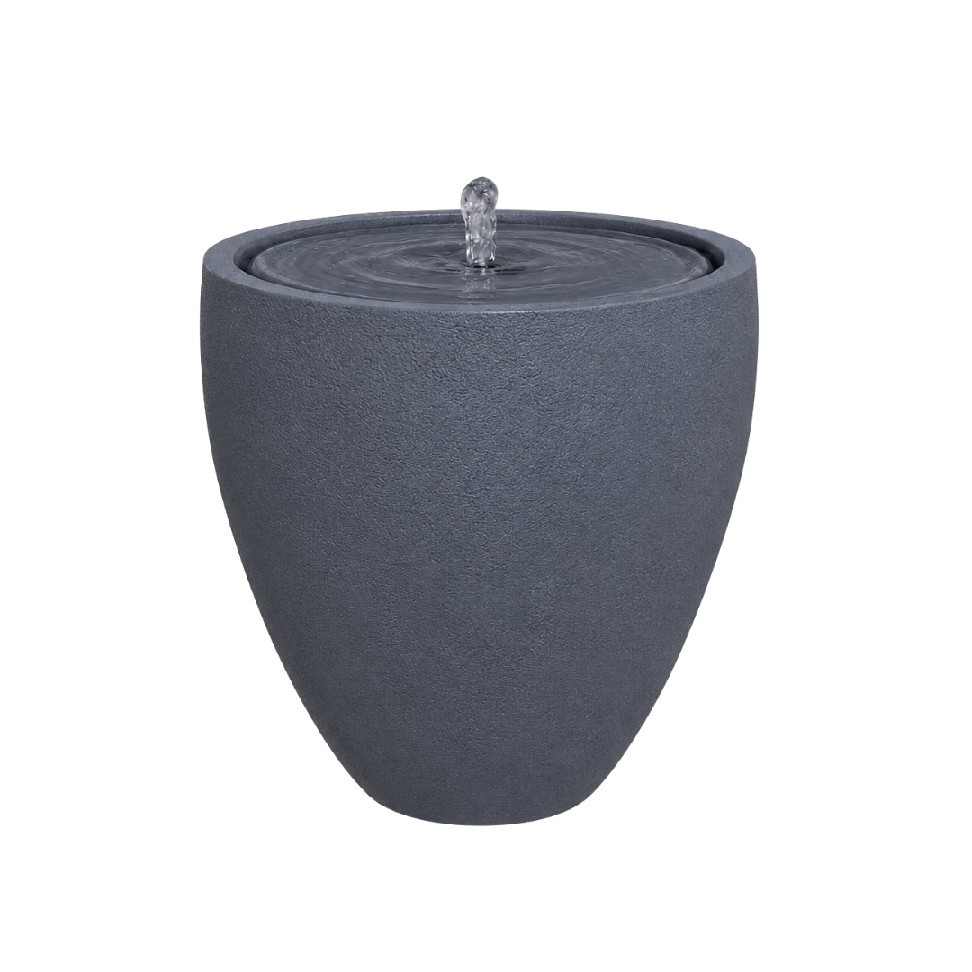 The Florastyle By Hingham Water Feature - Rustic Ellipse Small is a modern, dark gray, round textured planter-style fountain with water bubbling gently from the center. Perfect for indoor or outdoor use and shown here against a plain white background.