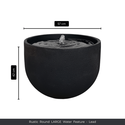 A large, round, rustic lead-colored water feature by Florastyle By Hingham with a central fountain. Measuring 57 cm diameter x 42 cm high. Text at the bottom: Water Feature - Rustic Round. Made from polyresin, durable and waterproof, yet lightweight. Suitable for indoor and outdoor spaces.
Colour: Lead
Price: R3625