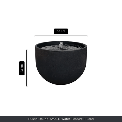 A round, black Water Feature - Rustic Round by Florastyle By Hingham, featuring a small central fountain. Measures 33 cm wide and 23 cm tall. Made from UV-resistant polyresin. Text: Water Feature - Rustic Round SMALL - Lead. Made from polyresin, durable and waterproof, yet lightweight. Suitable for indoor and outdoor spaces.
Colour: Lead
Price: R1495
