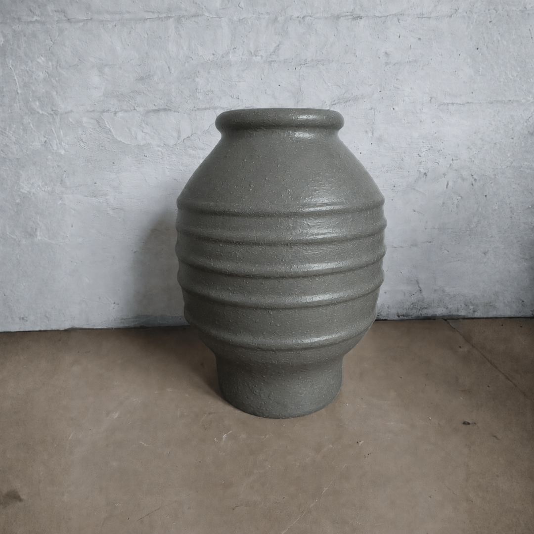 The Sparta Organic Fiberglass Pot - Earth Range by Florastyle By Hingham features a gray, textured finish, rounded body, three ridges, and a narrow opening—ideal as a modern indoor planter for any space.